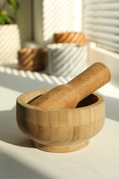 Photo of Wooden mortar and pestle on windowsill indoors, closeup