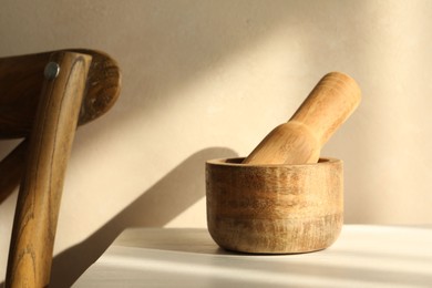 Photo of Wooden mortar and pestle on white table indoors, closeup