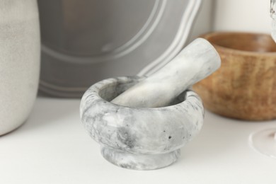 Photo of Marble mortar and pestle on white table indoors, closeup