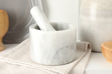 Photo of Marble mortar and pestle on white table indoors, closeup