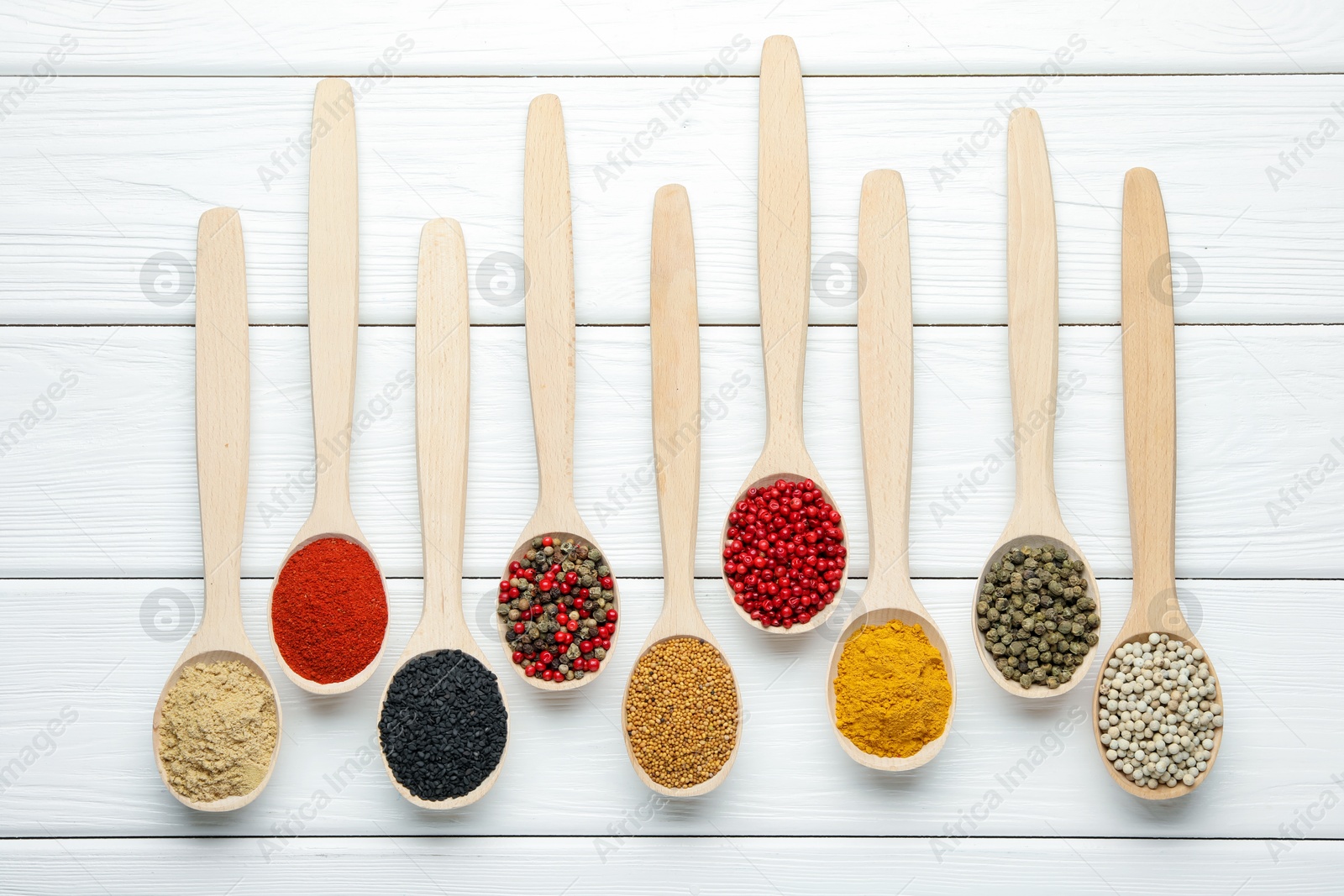 Different aromatic spices in spoons on white wooden table, flat lay Photo of Different aromatic spices in spoons on white wooden table, flat lay