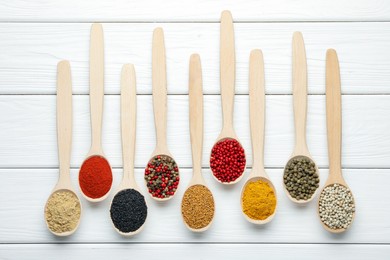 Photo of Different aromatic spices in spoons on white wooden table, flat lay