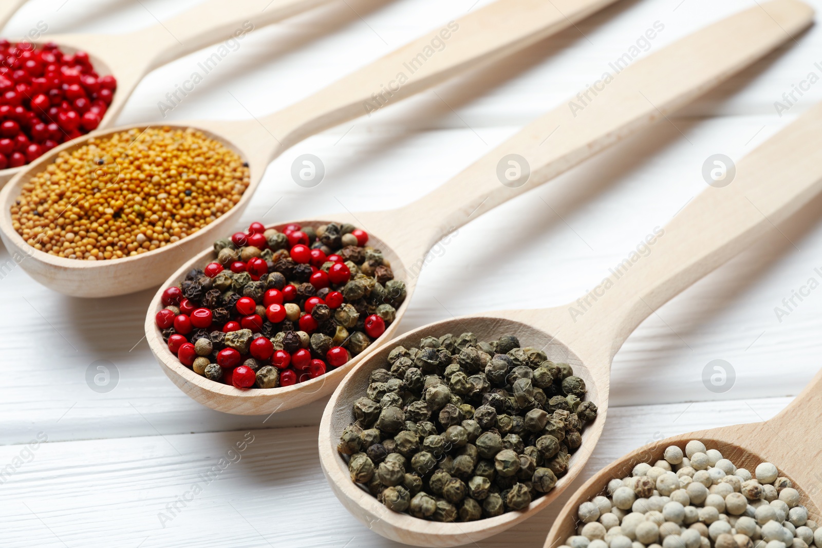Different aromatic spices in spoons on white wooden table, closeup Photo of Different aromatic spices in spoons on white wooden table, closeup