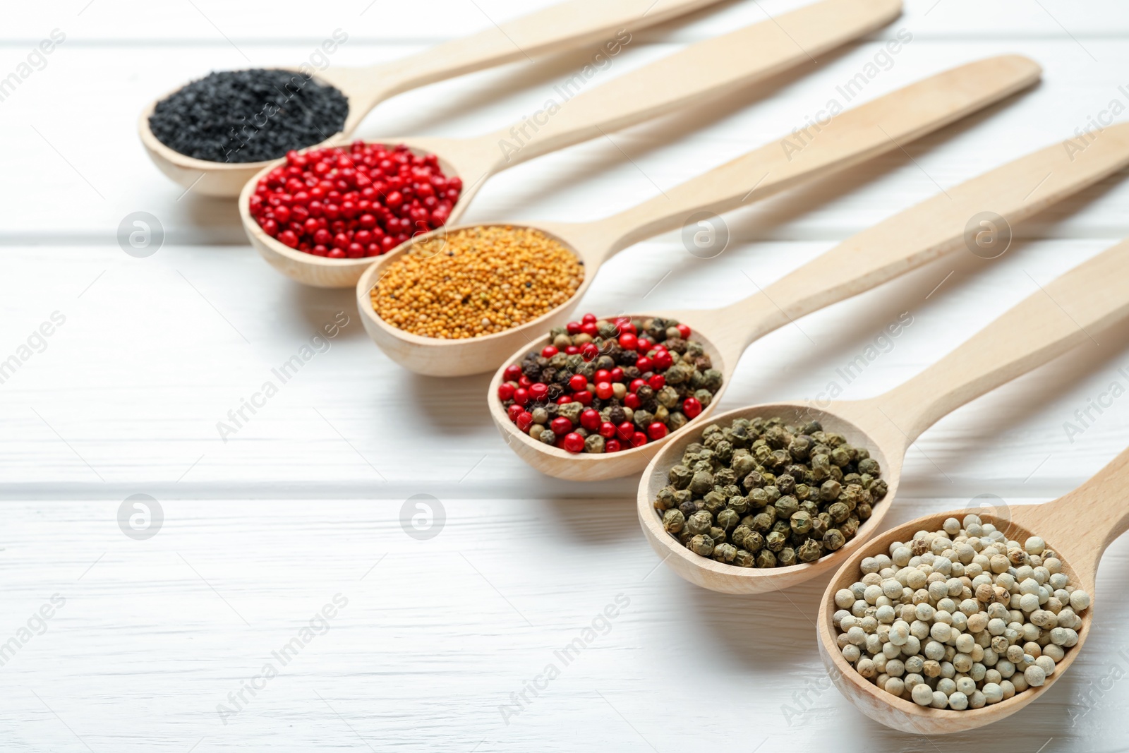 Different aromatic spices in spoons on white wooden table, closeup Photo of Different aromatic spices in spoons on white wooden table, closeup