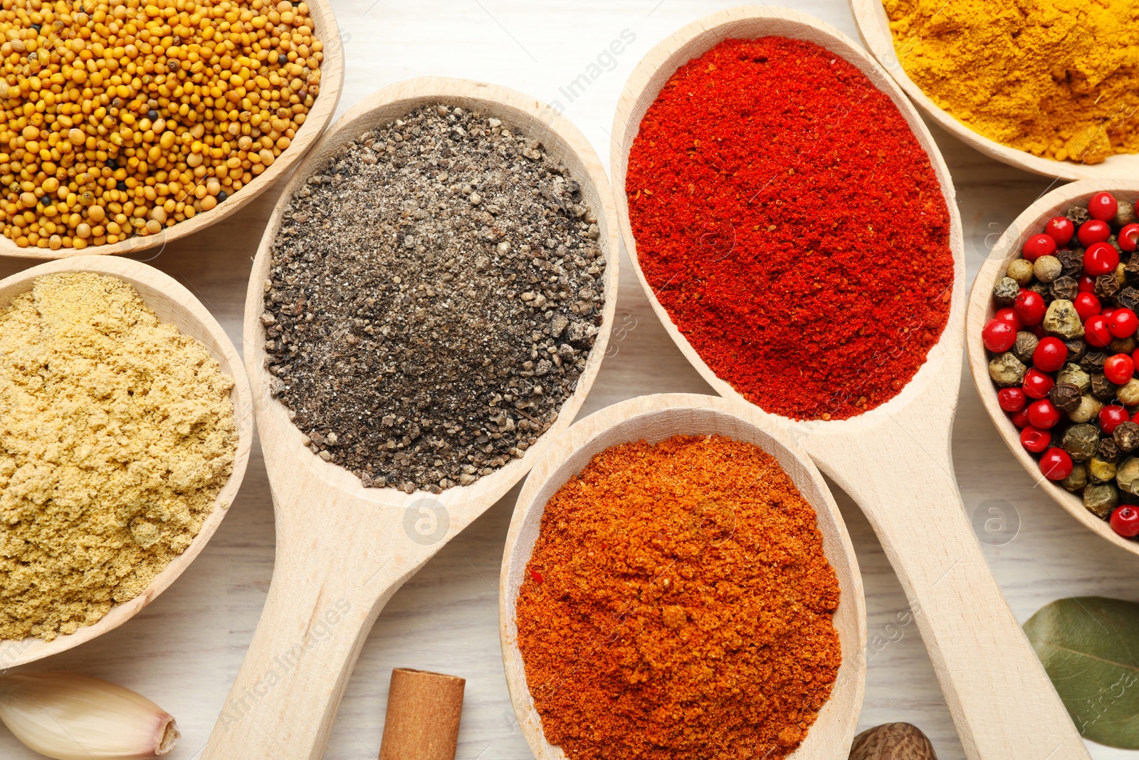 Different aromatic spices in spoons on white wooden table, flat lay Photo of Different aromatic spices in spoons on white wooden table, flat lay