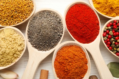 Photo of Different aromatic spices in spoons on white wooden table, flat lay