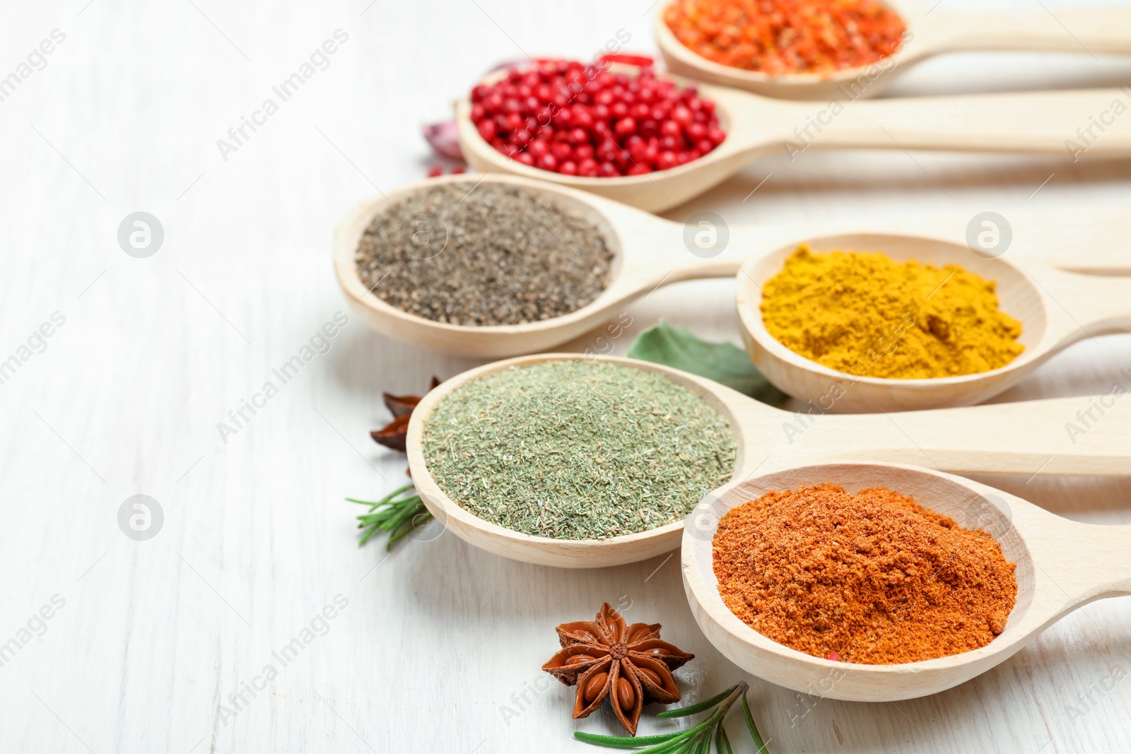 Different aromatic spices in spoons on white wooden table, closeup Photo of Different aromatic spices in spoons on white wooden table, closeup