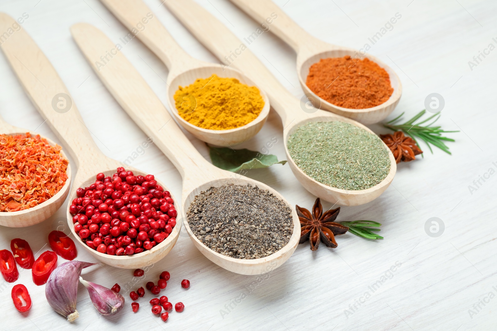 Different aromatic spices in spoons on white wooden table, closeup Photo of Different aromatic spices in spoons on white wooden table, closeup