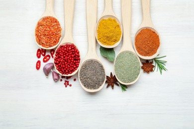 Photo of Different aromatic spices in spoons on white wooden table, flat lay