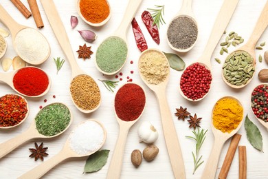 Photo of Different aromatic spices in spoons on white wooden table, flat lay