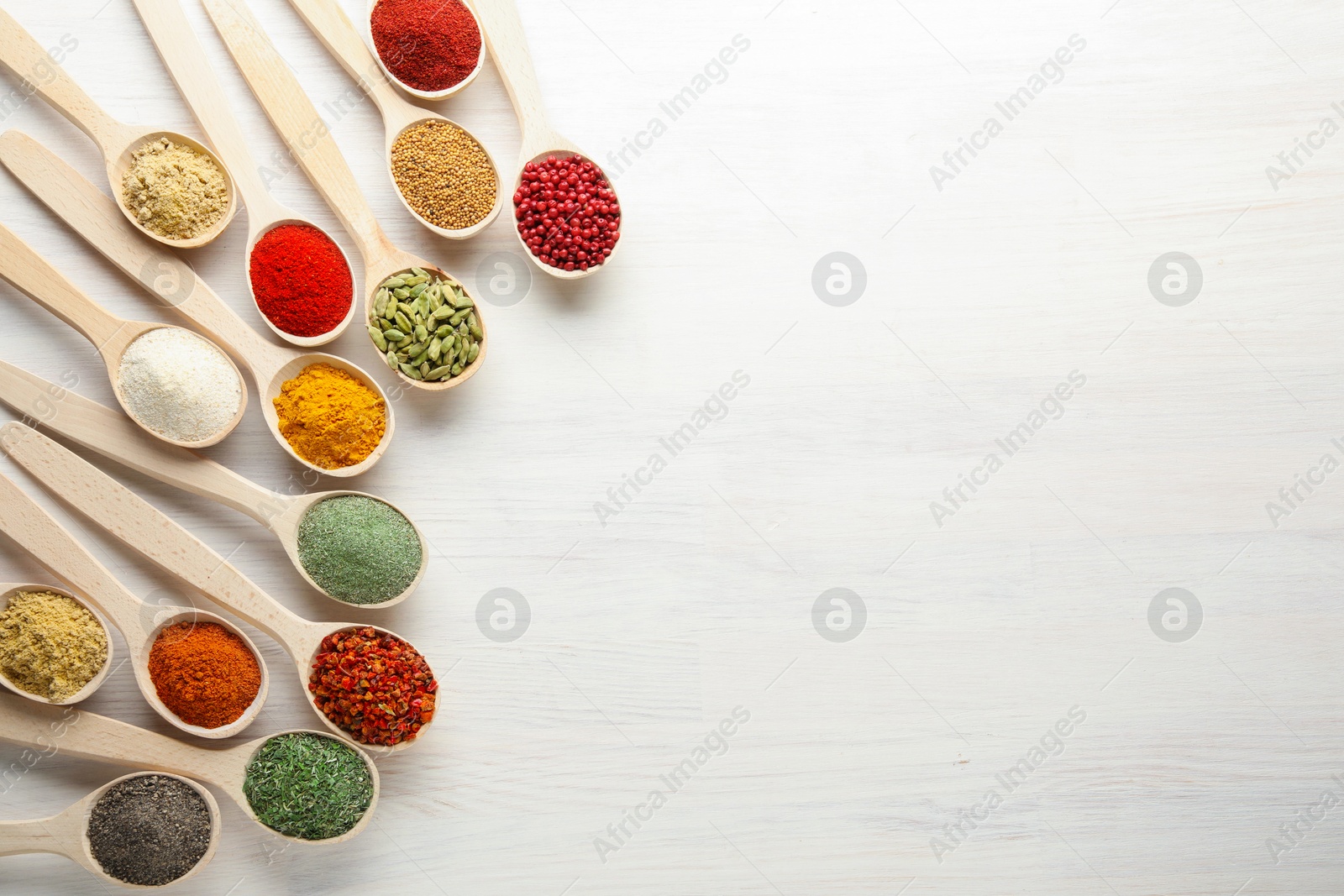 Different aromatic spices in spoons on white wooden table, flat lay. Space for text Photo of Different aromatic spices in spoons on white wooden table, flat lay. Space for text