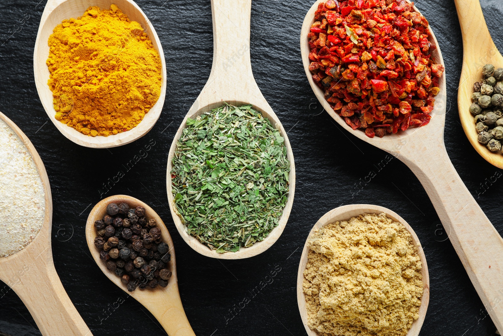 Different aromatic spices in spoons on black table, closeup Photo of Different aromatic spices in spoons on black table, closeup