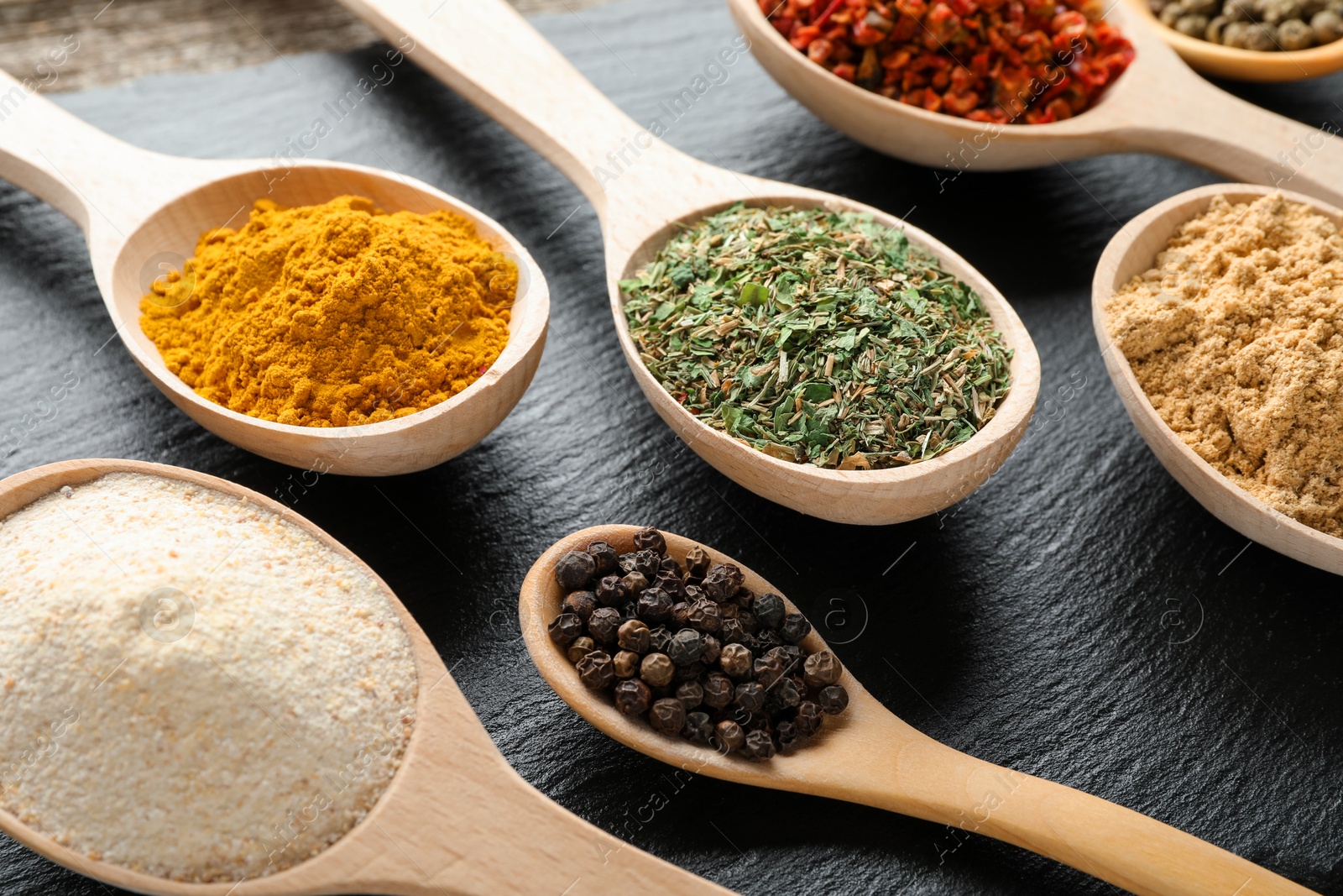 Different aromatic spices in spoons on black table, closeup Photo of Different aromatic spices in spoons on black table, closeup