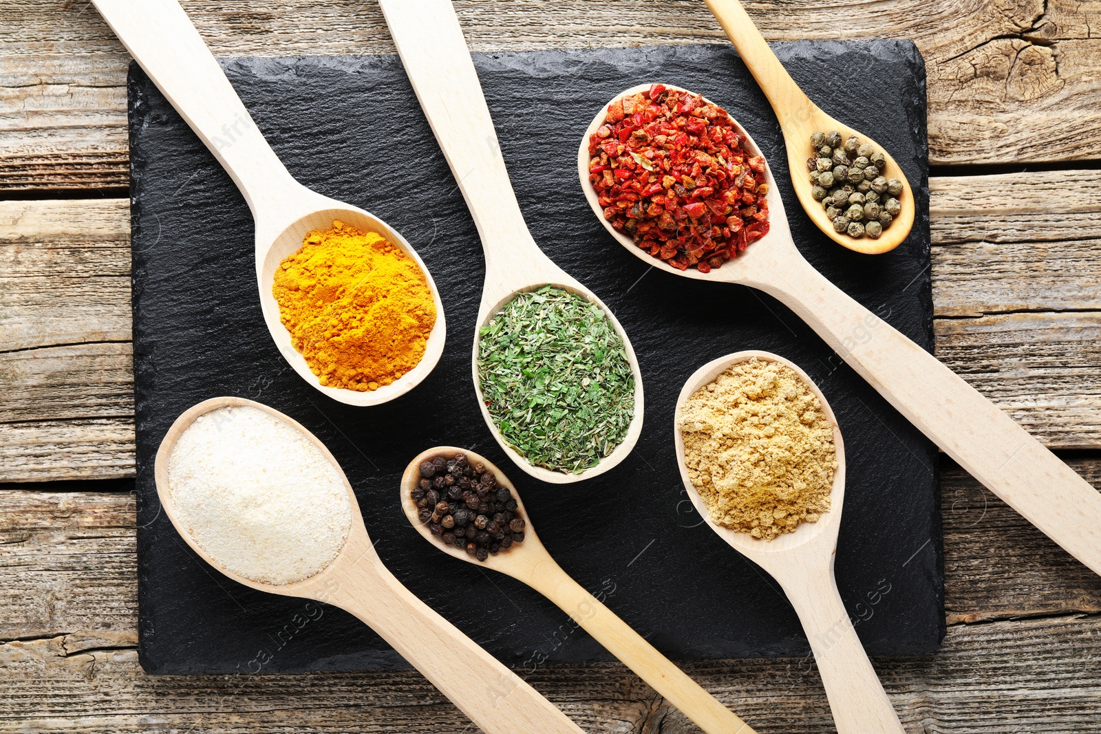 Different aromatic spices in spoons on wooden table, flat lay Photo of Different aromatic spices in spoons on wooden table, flat lay