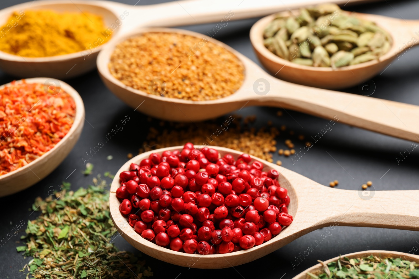 Different aromatic spices in spoons on black table, closeup Photo of Different aromatic spices in spoons on black table, closeup