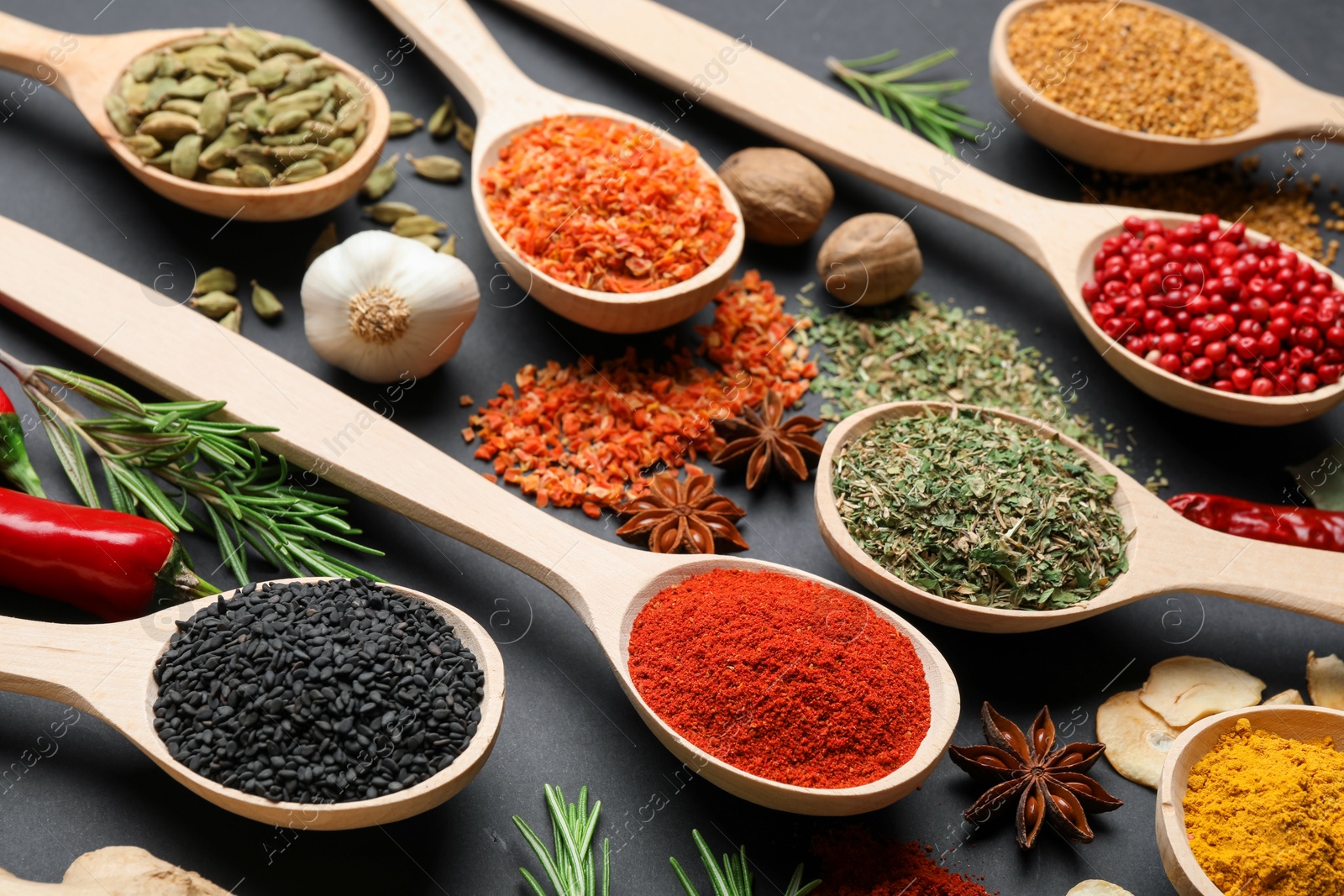 Different aromatic spices in spoons on black table, closeup Photo of Different aromatic spices in spoons on black table, closeup