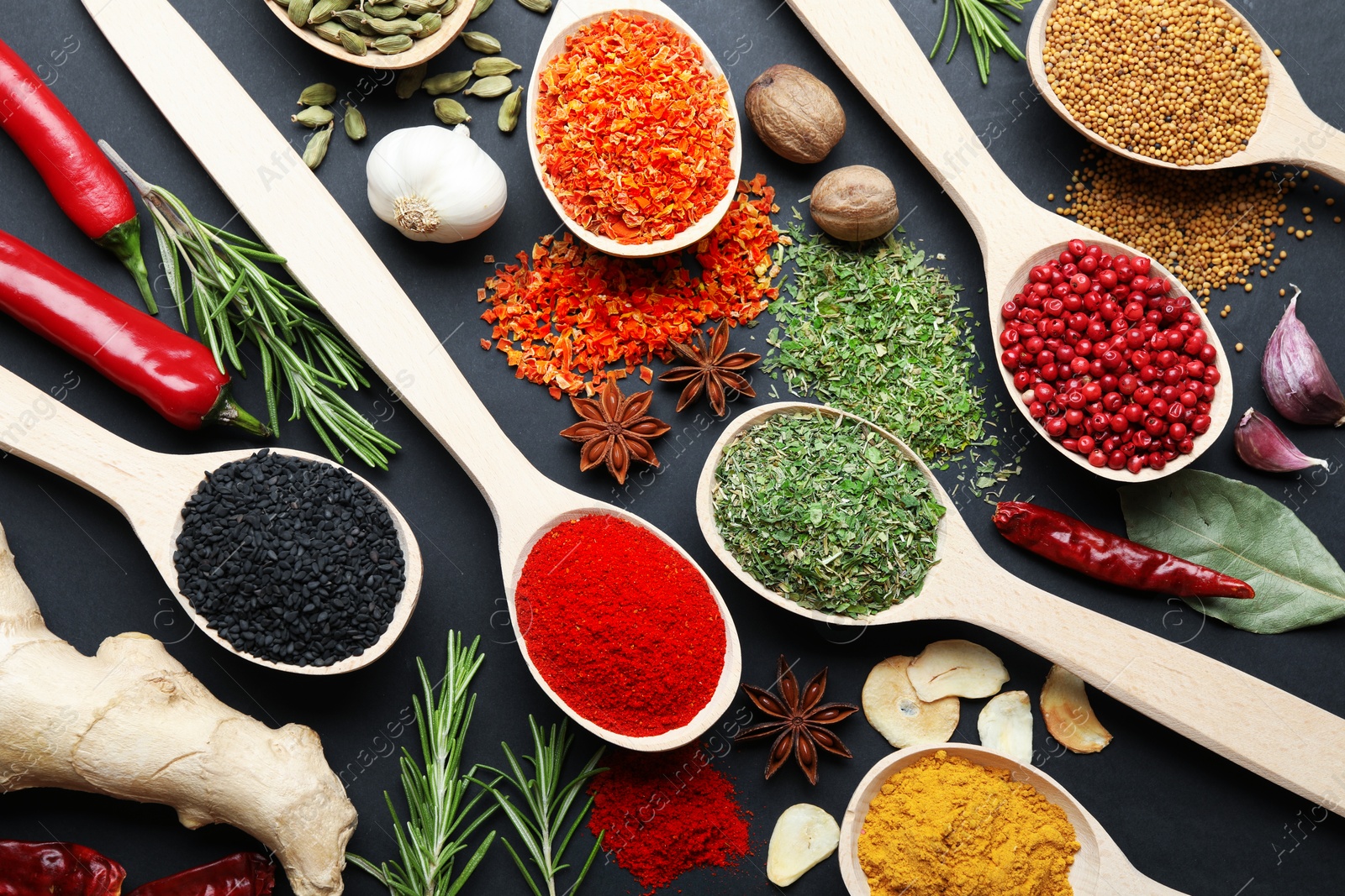 Different aromatic spices in spoons on black table, flat lay Photo of Different aromatic spices in spoons on black table, flat lay