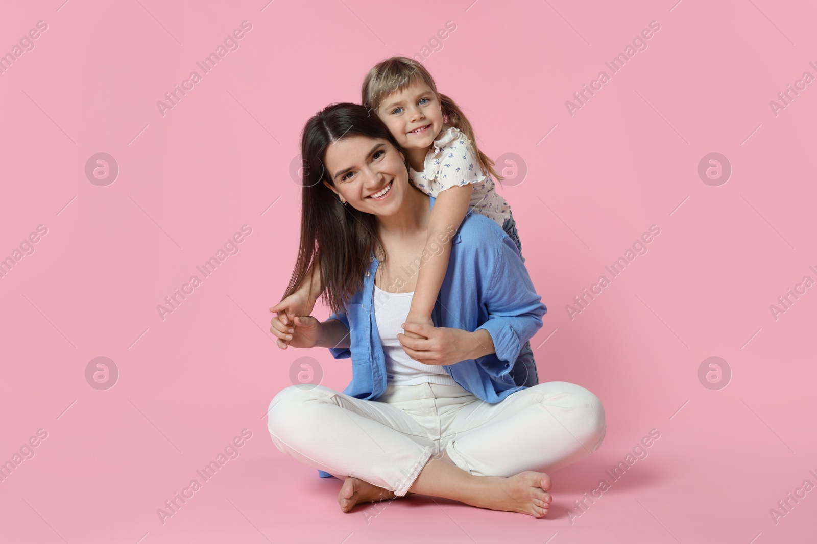 Photo of Happy mother and her cute daughter on pink background