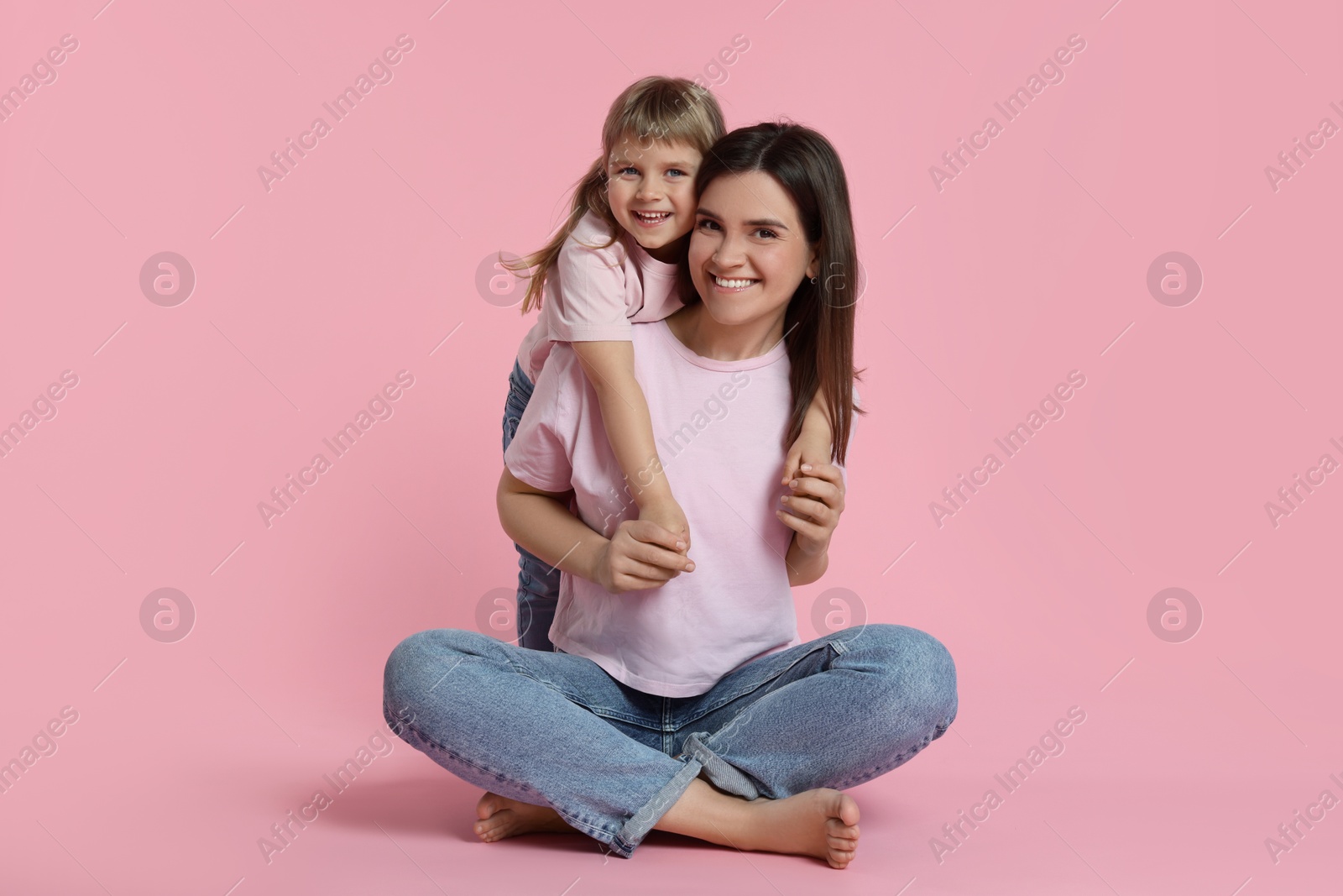 Happy mother and her cute daughter on pink background Photo of Happy mother and her cute daughter on pink background