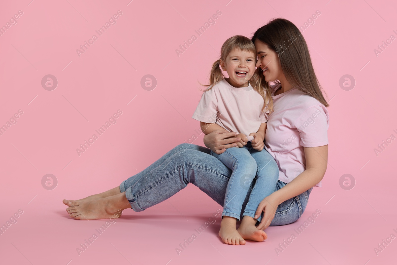 Happy mother and her cute daughter on pink background Photo of Happy mother and her cute daughter on pink background