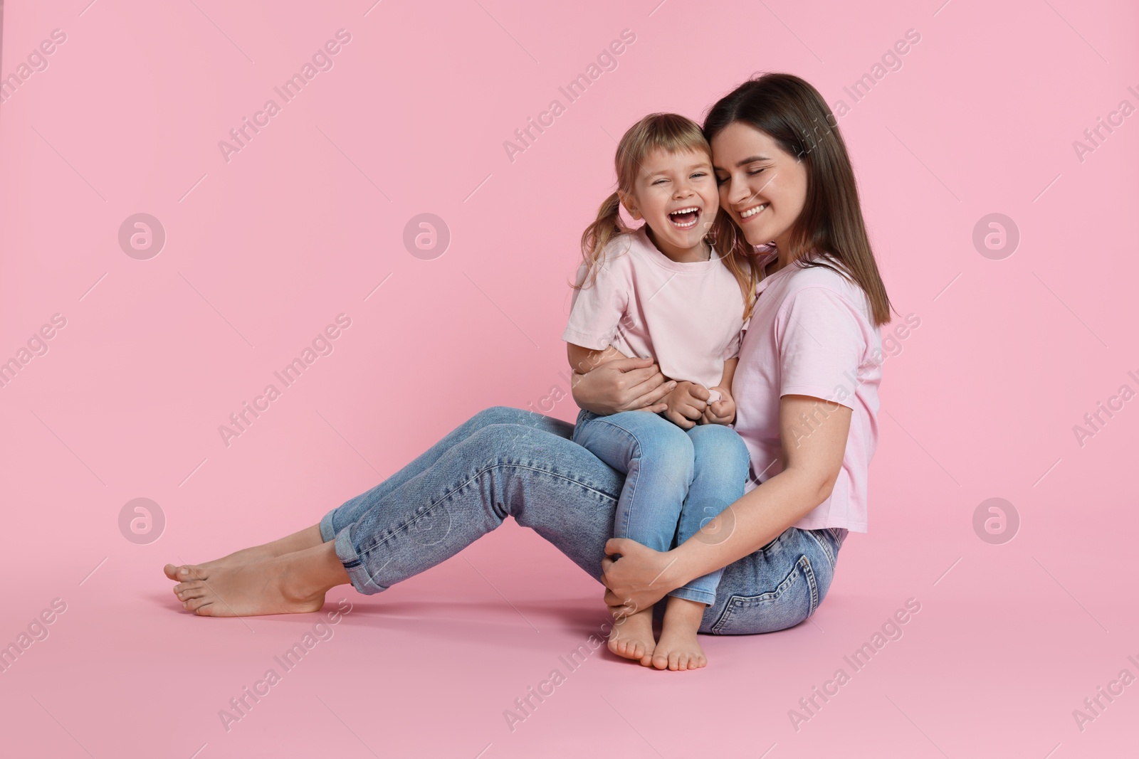 Happy mother and her cute daughter on pink background Photo of Happy mother and her cute daughter on pink background