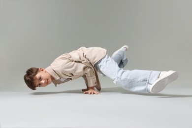 Photo of Boy in stylish clothes dancing on light grey background