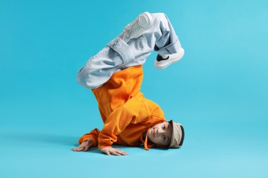Photo of Boy in stylish clothes dancing on light blue background