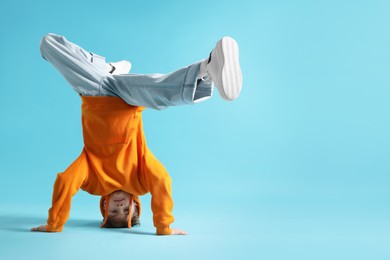 Photo of Boy in stylish clothes dancing on light blue background, space for text
