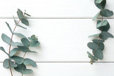 Photo of Eucalyptus branches on white wooden table, flat lay. Space for text