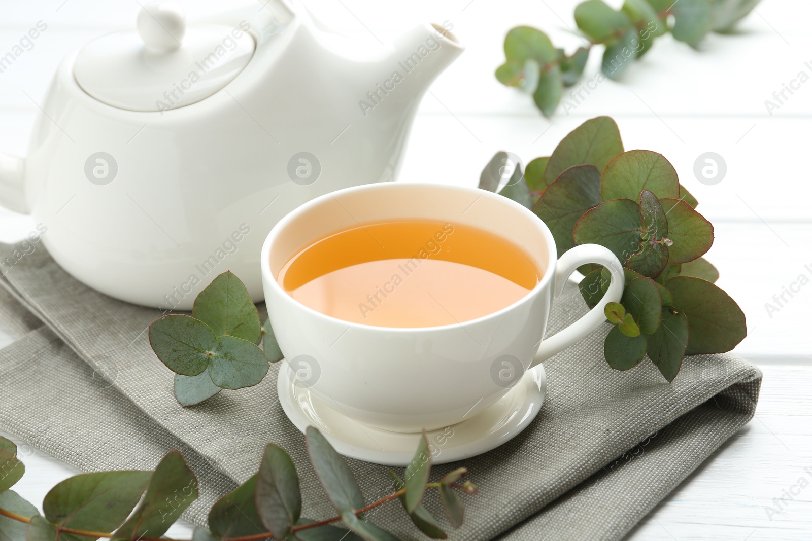 Aromatic tea in cup and eucalyptus branches on white wooden table, closeup Photo of Aromatic tea in cup and eucalyptus branches on white wooden table, closeup