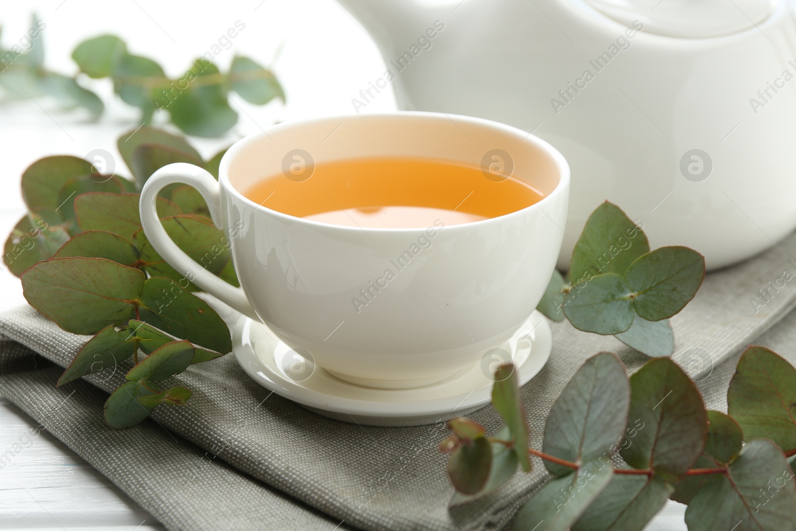 Aromatic tea in cup and eucalyptus branches on table, closeup Photo of Aromatic tea in cup and eucalyptus branches on table, closeup