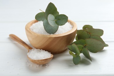 Photo of Sea salt and beautiful eucalyptus branches on white wooden table, closeup