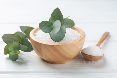 Photo of Sea salt and beautiful eucalyptus branches on white wooden table, closeup