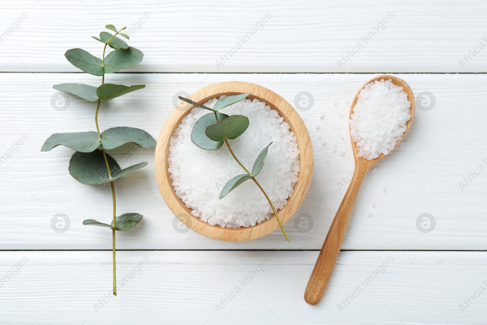 Sea salt and beautiful eucalyptus branches on white wooden table, flat lay Photo of Sea salt and beautiful eucalyptus branches on white wooden table, flat lay