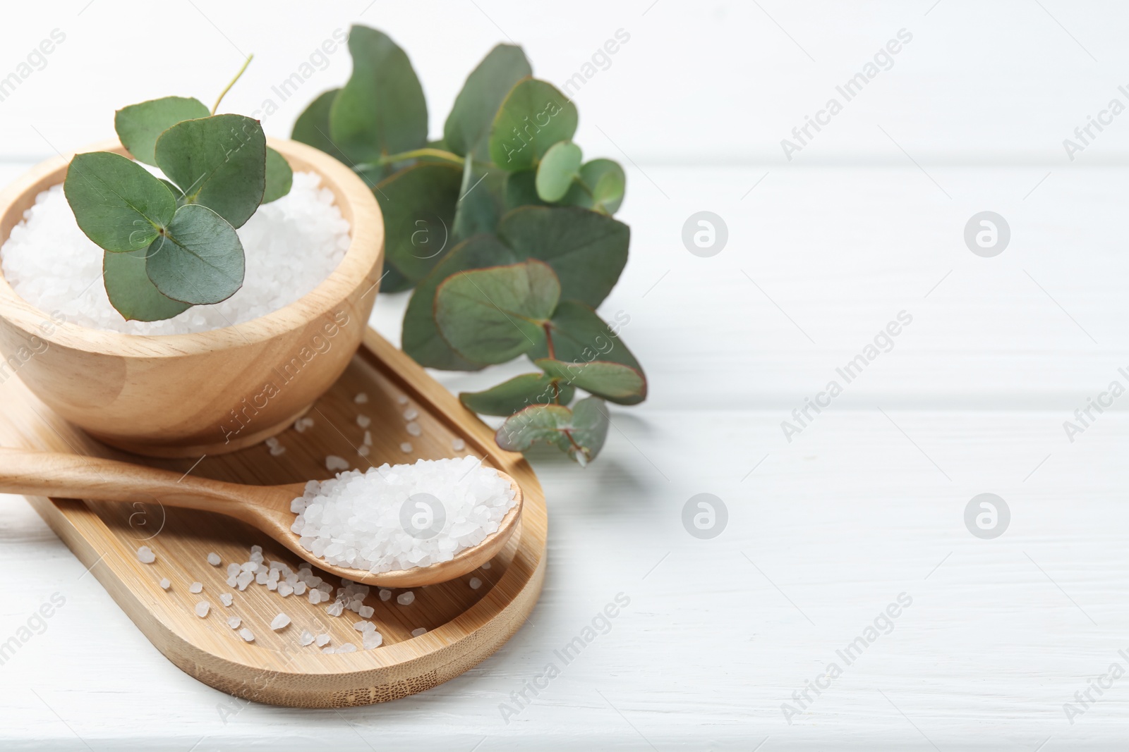 Sea salt and beautiful eucalyptus branches on white wooden table, closeup. Space for text Photo of Sea salt and beautiful eucalyptus branches on white wooden table, closeup. Space for text