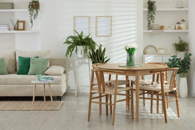 Photo of Comfortable sofa, table, chairs and green houseplants indoors. Interior design