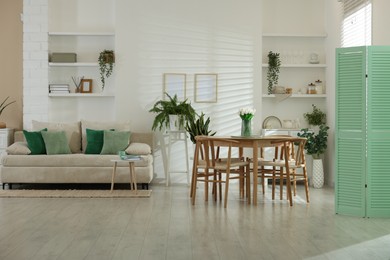 Photo of Comfortable sofa, table, chairs and green houseplants indoors. Interior design