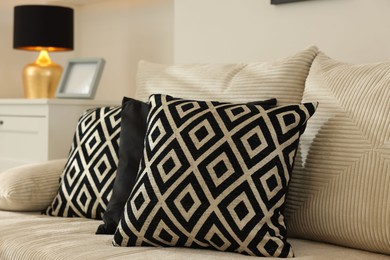 Photo of Comfortable sofa with pillows and dresser indoors. Interior design