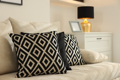 Photo of Comfortable sofa with pillows and dresser indoors. Interior design