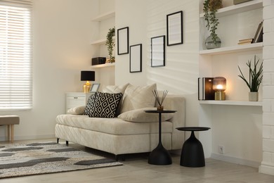 Photo of Comfortable sofa, nesting tables and different decor indoors. Interior design