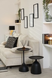 Photo of Comfortable sofa, nesting tables and different decor indoors. Interior design