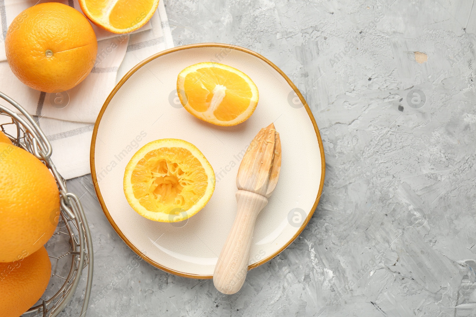 Wooden juicer and fresh oranges on grey table, flat lay. Space for text Photo of Wooden juicer and fresh oranges on grey table, flat lay. Space for text