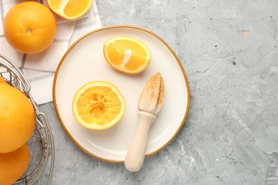 Photo of Wooden juicer and fresh oranges on grey table, flat lay. Space for text