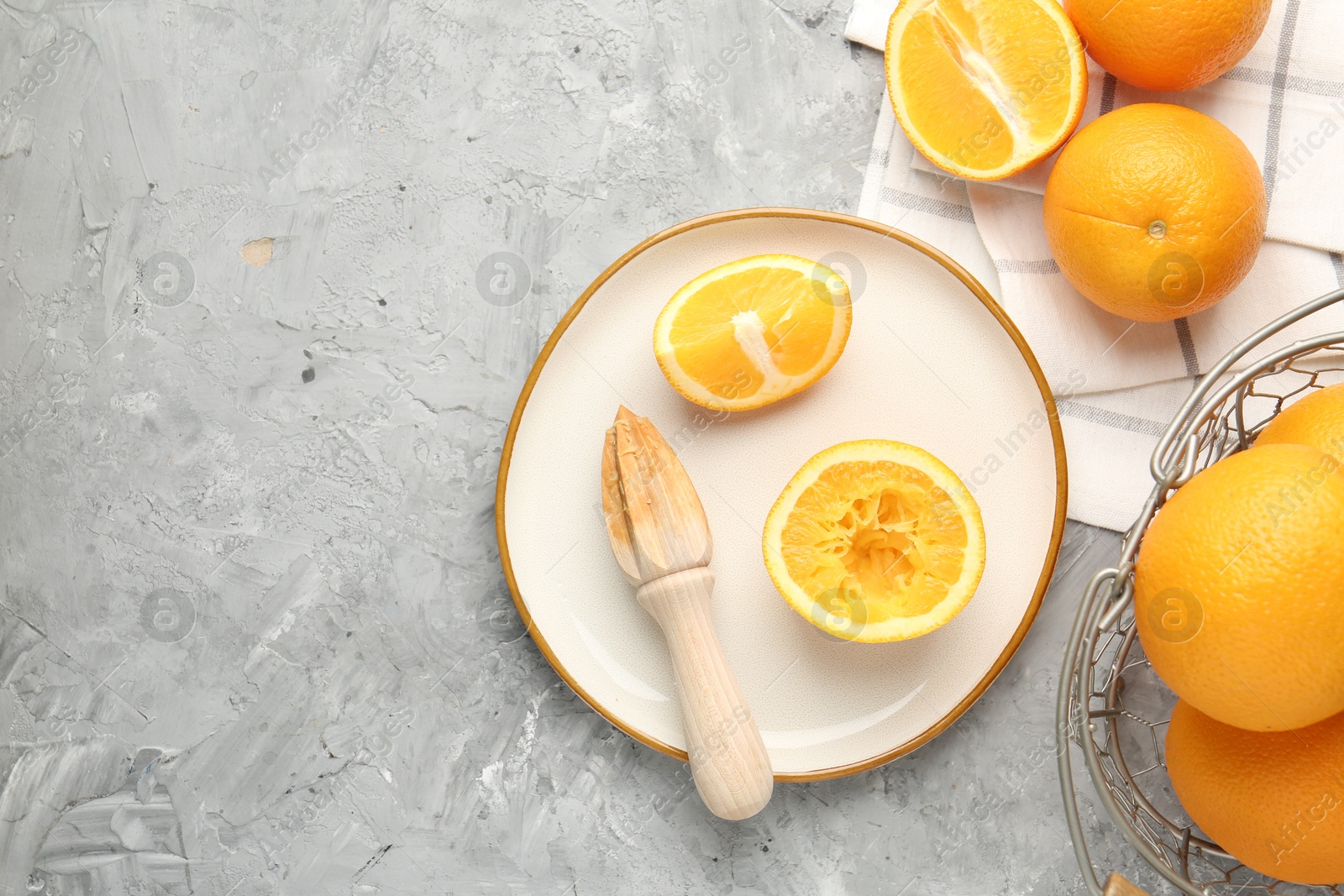 Wooden juicer and fresh oranges on grey table, flat lay. Space for text Photo of Wooden juicer and fresh oranges on grey table, flat lay. Space for text