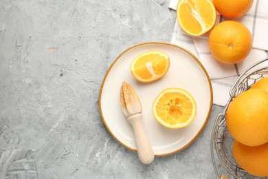 Photo of Wooden juicer and fresh oranges on grey table, flat lay. Space for text