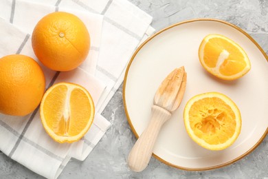 Photo of Wooden juicer and fresh oranges on grey table, flat lay