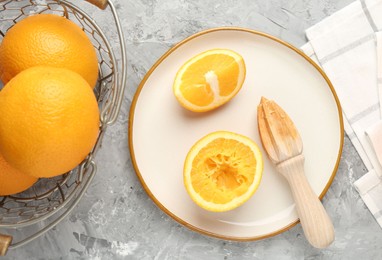 Photo of Wooden juicer and fresh oranges on grey table, flat lay
