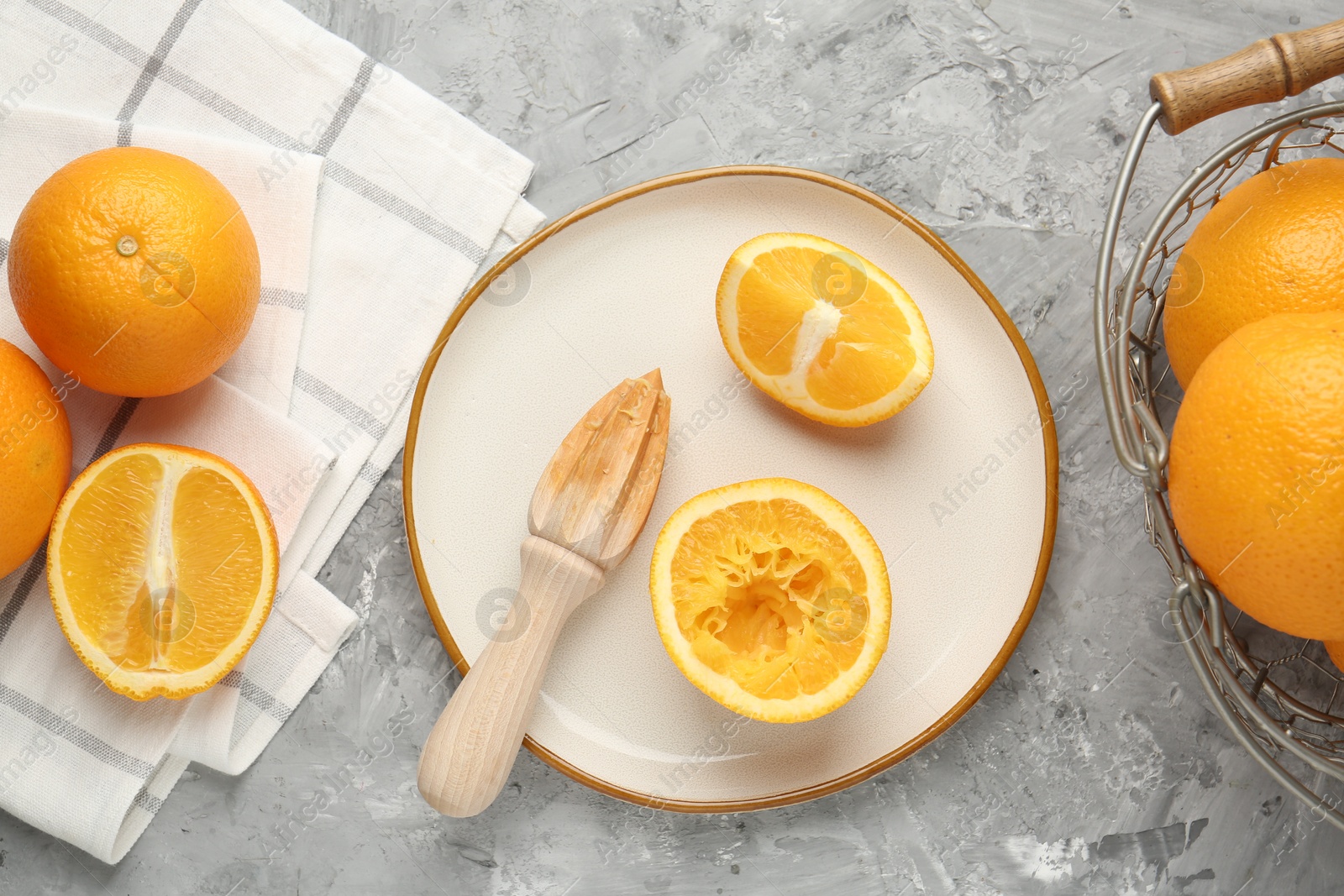 Wooden juicer and fresh oranges on grey table, flat lay Photo of Wooden juicer and fresh oranges on grey table, flat lay