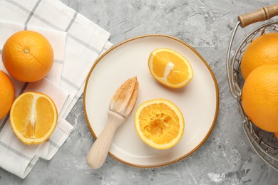 Photo of Wooden juicer and fresh oranges on grey table, flat lay