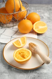 Photo of Wooden juicer and fresh oranges on grey table, closeup